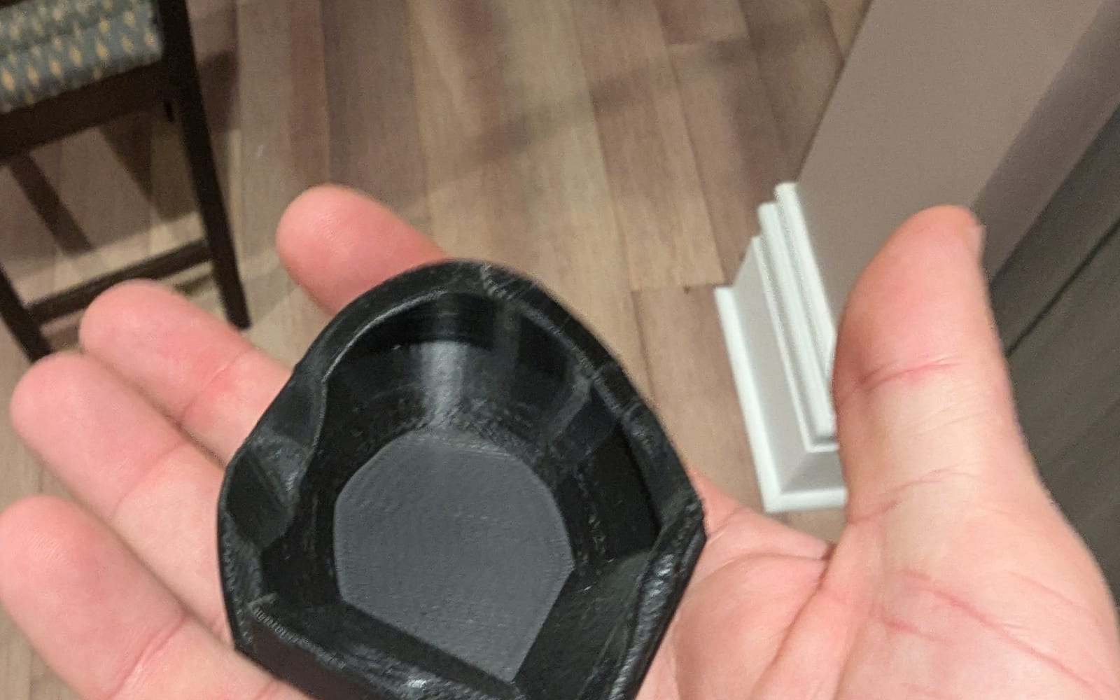 The black 3D-printed hand guard held in an open palm